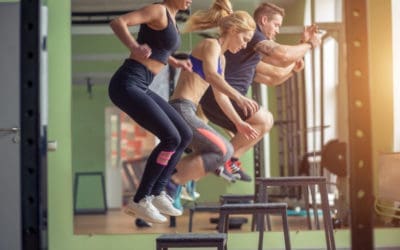 Male and female athletes doing box jumps at gym